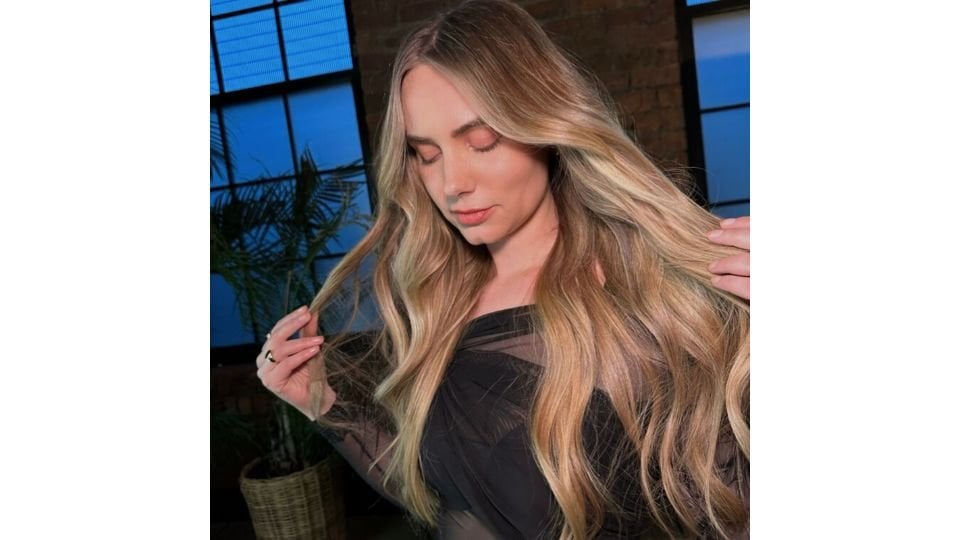 An Instagram reel from L’Oreal Professionnel depicting a hair stylist unveiling a hair colour transformation from dark to cherry cola shade on a woman with brown eyes