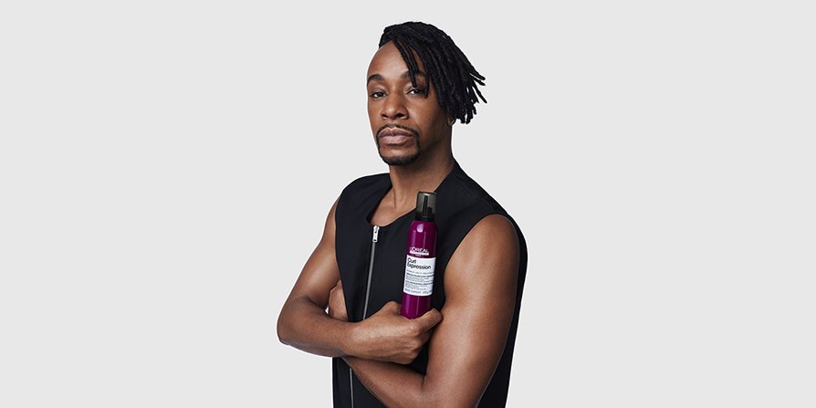 Focus on a man with styled coily hair holding Curl Expression Serum, illustrating L’Oréal Men Curly Hair Care routine for all curls.