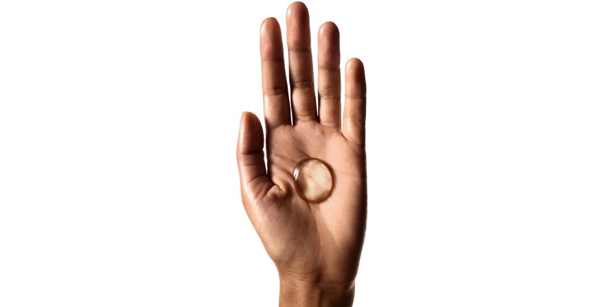 Focus on a hand holding a drop of shampoo, illustrating that using the right amount and application method helps reduce oily hair.