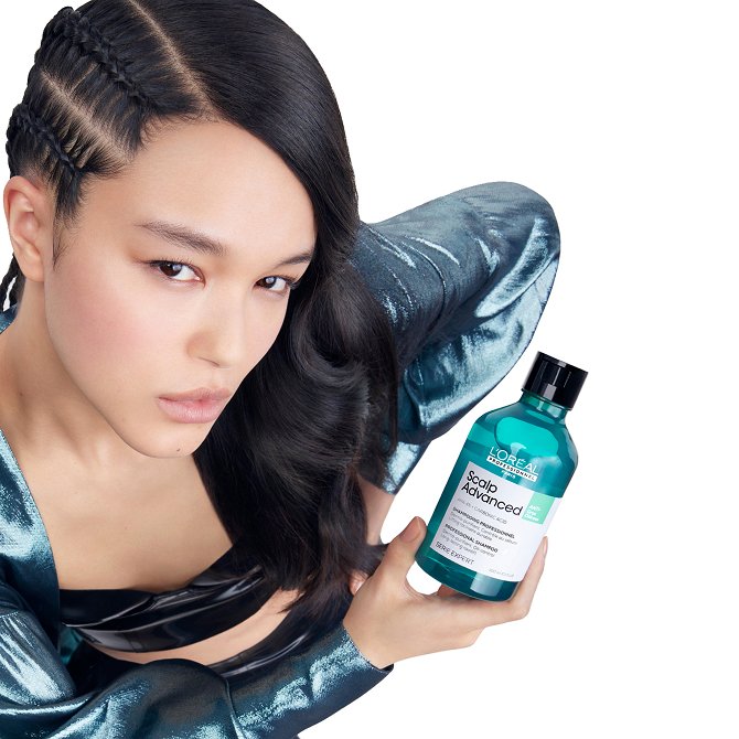 Woman holding a bottle of L’Oréal Scalp Advanced Shampoo, presenting the range designed to get rid of oily hair.
