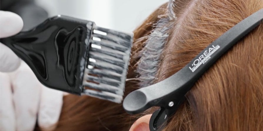Focus on a woman at the salon having her hair dyed by a professional, illustrating how to achieve the trendy Espresso Brunette color.