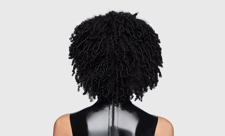 Woman from behind with shiny, healthy defined curls, illustrating tips and care techniques to maintain nourished, coily hair.